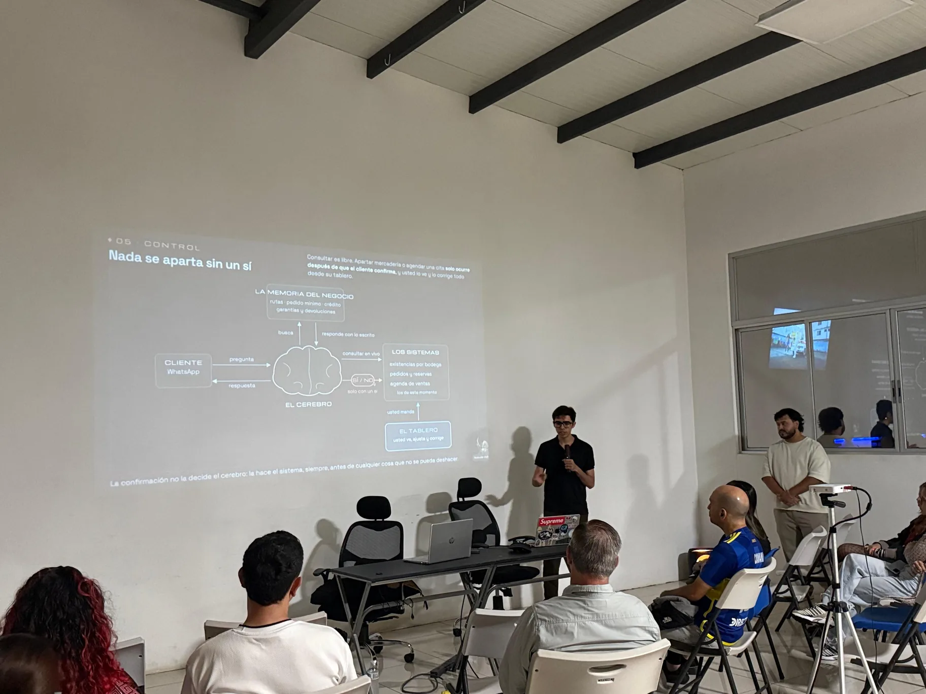 Two presenters walk an audience through an automation and AI diagram